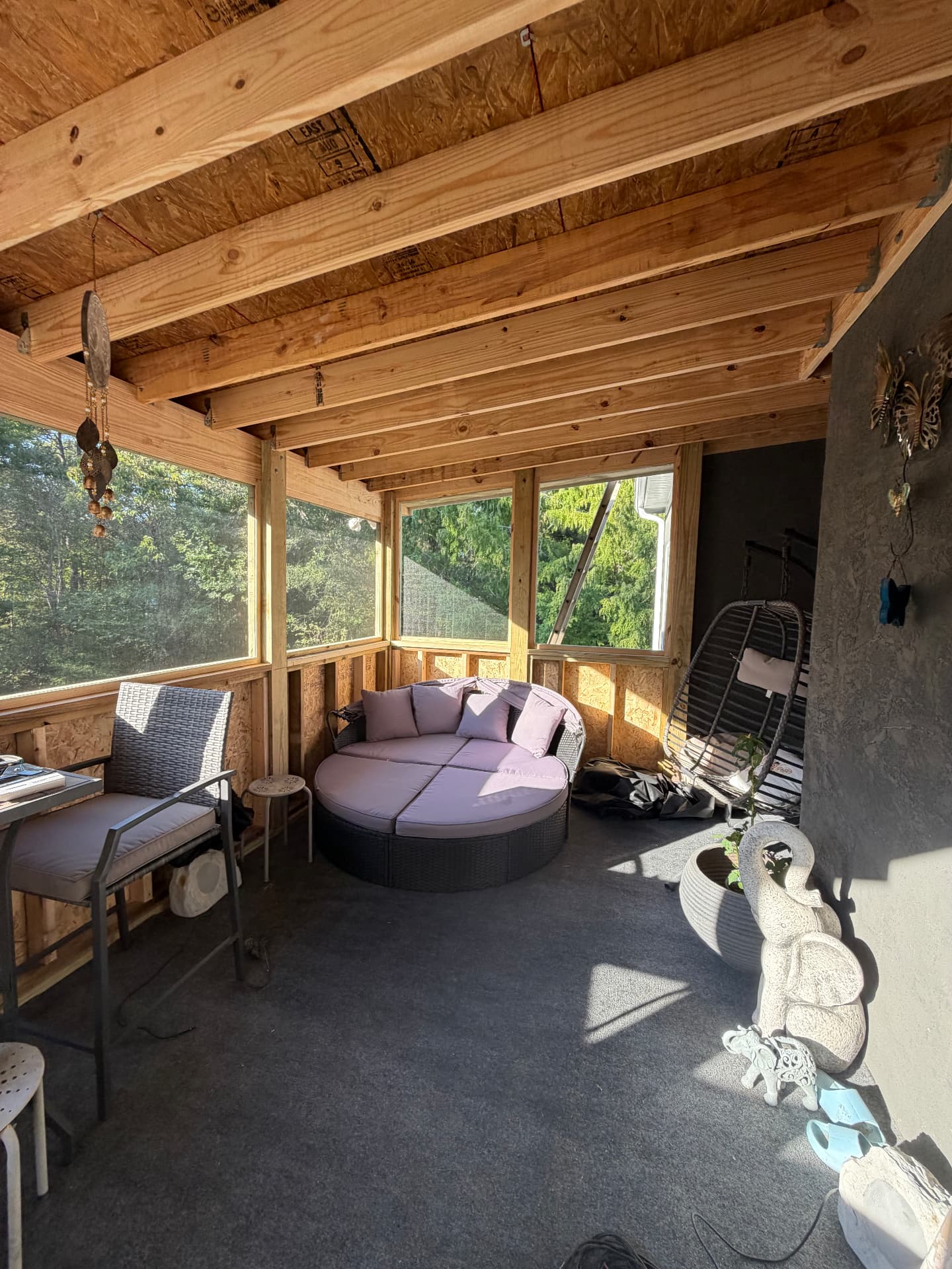 Interior of a screened porch with exposed wood beams, lounge seating and garden views