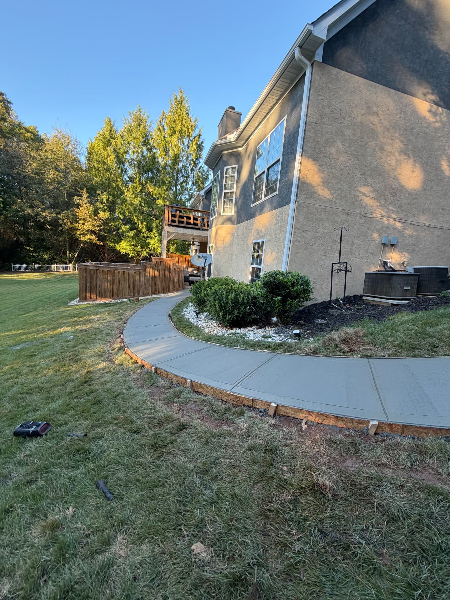 Finished concrete walkway curving along a home through the lawn