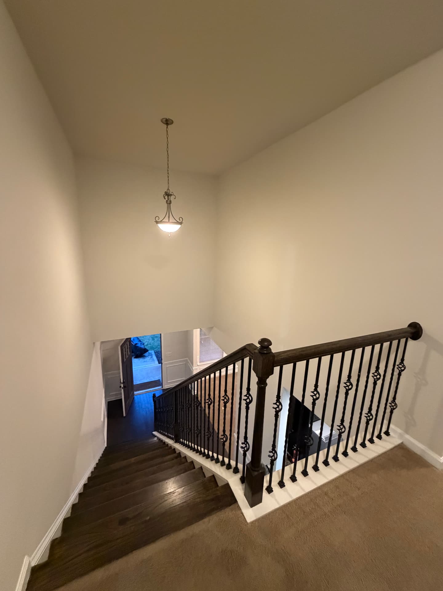 Two-storey stairwell with fresh warm off-white walls, white trim and a dark handrail