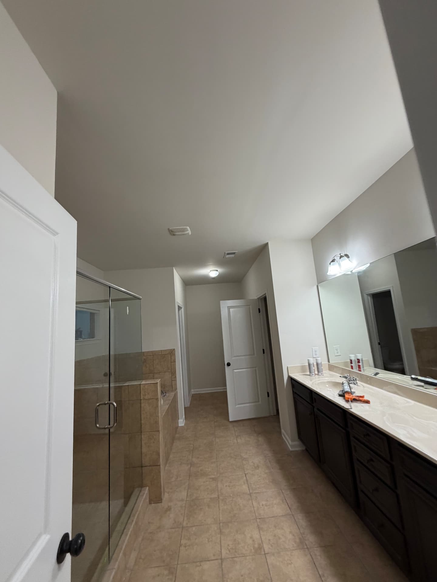 Primary bathroom with a double vanity and frameless mirror, walls freshly painted pale greige