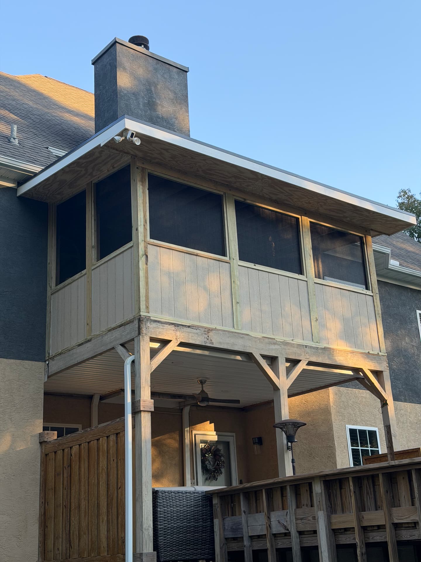 Close view of a newly built screened porch with timber posts and a ceiling fan