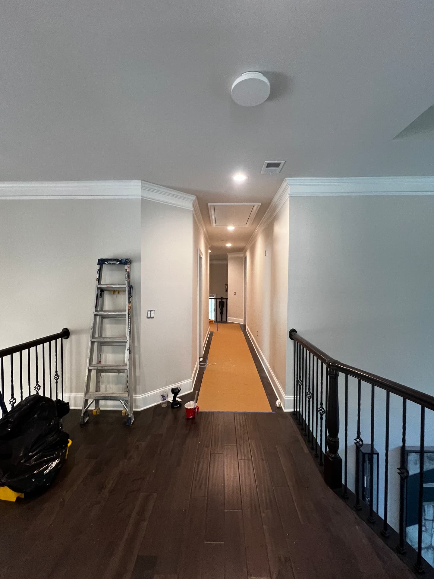 Upstairs landing with dark railings, freshly painted walls and crown moulding