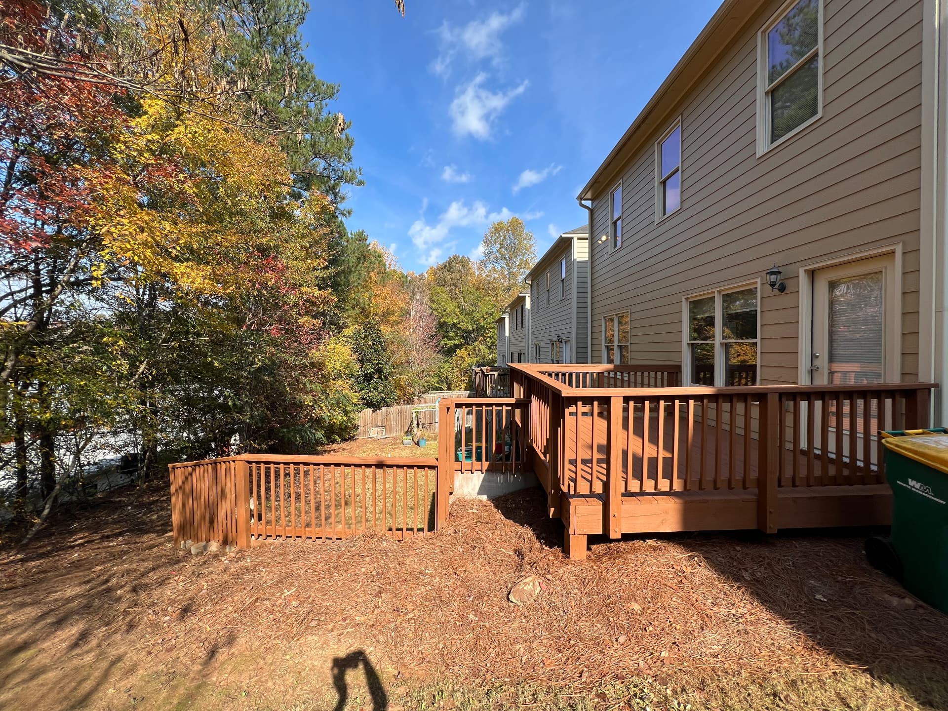 Freshly stained reddish-brown deck with tan siding and off-white trim