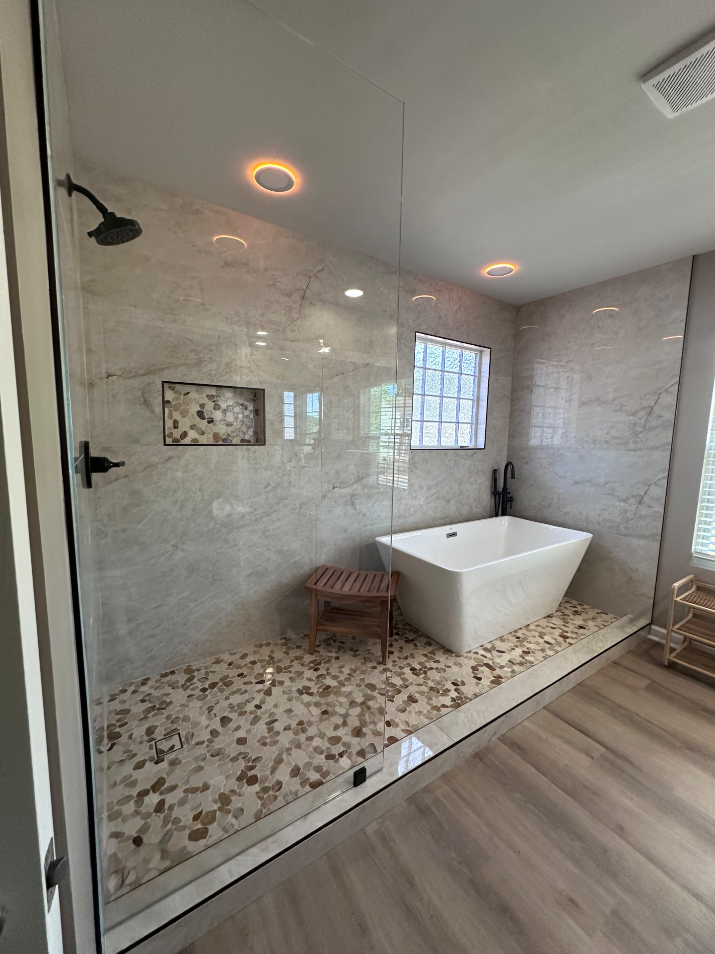 Luxury bathroom with marble-look walls, glass shower and a freestanding soaking tub