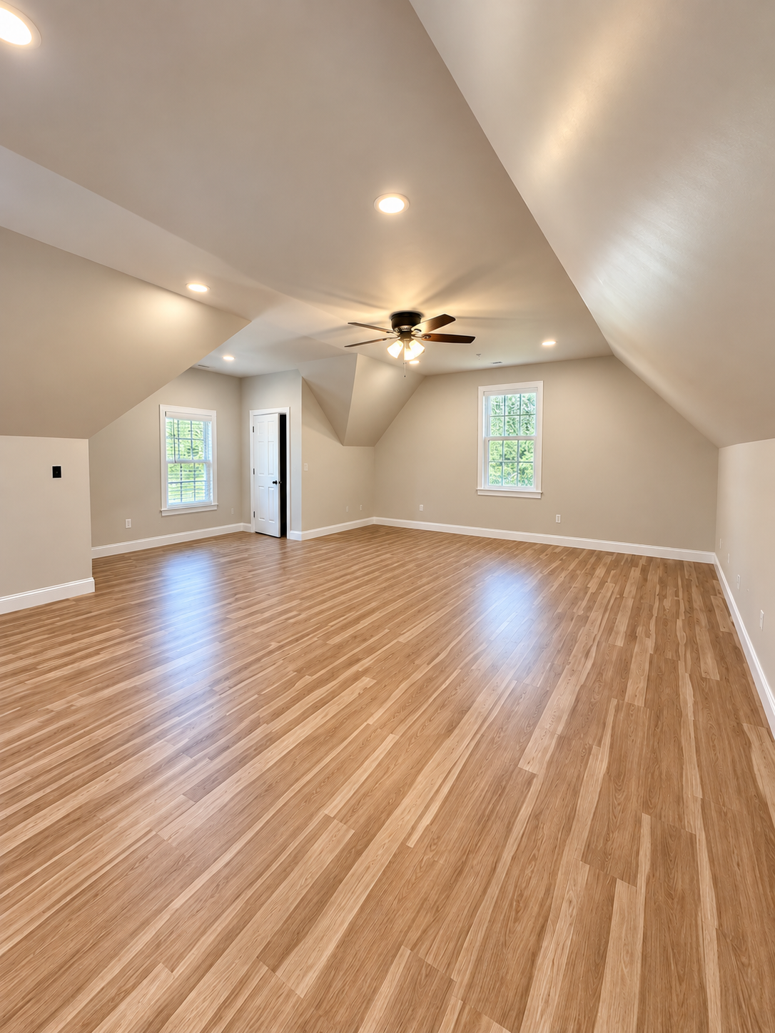 Finished bonus room with fresh walls, white trim and warm wood flooring